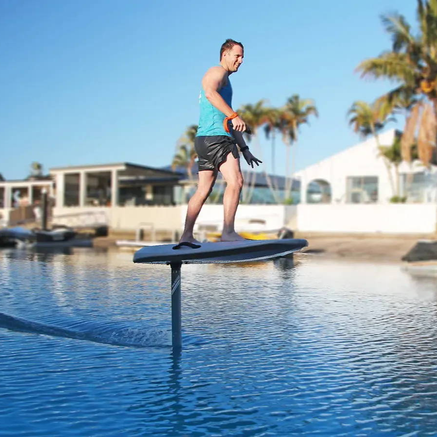 Person standing on a Flyer EVO in a pool with palm trees and buildings in the background